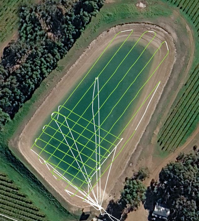 Aerial coverage map of a farm dam: the drone's parallel spreading passes drawn in green across the whole water surface, with its transit lines in white